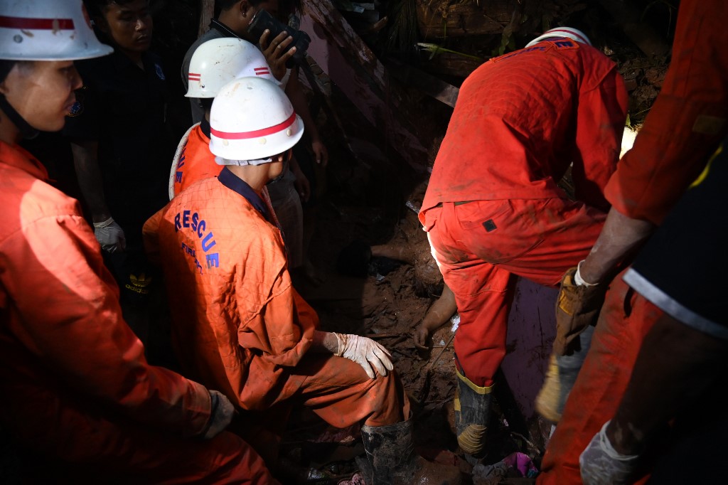Rescue workers attempt to extricate the body of a landslide victim from debris in Paung township, Mon state on August 9, 2019. (Ye Aung Thu / AFP)