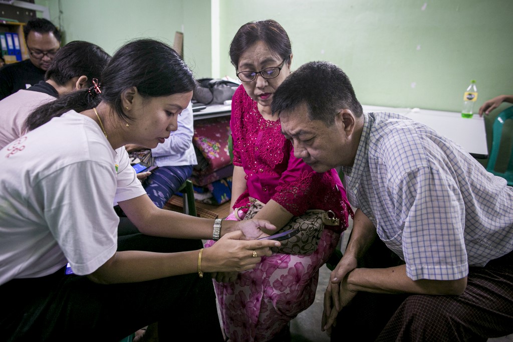 This photograph taken on September 22, 2019 shows Myanmar information technology volunteers assisting mobile phone users switching from the old Zawgyi font to the unicode font in Yangon. (Sai Aung Main / AFP)