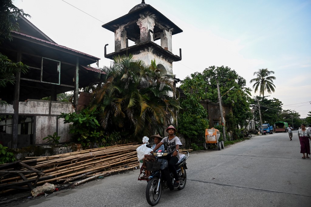 This photo taken on October 3, 2019 shows a man driving his motorcycle past the ruins of a mosque in Kyaukphyu, Rakhine state, where Muslim residents have been forced to live in a camp for seven years after the inter-communal unrest tore apart the town. (Ye Aung Thu / AFP)