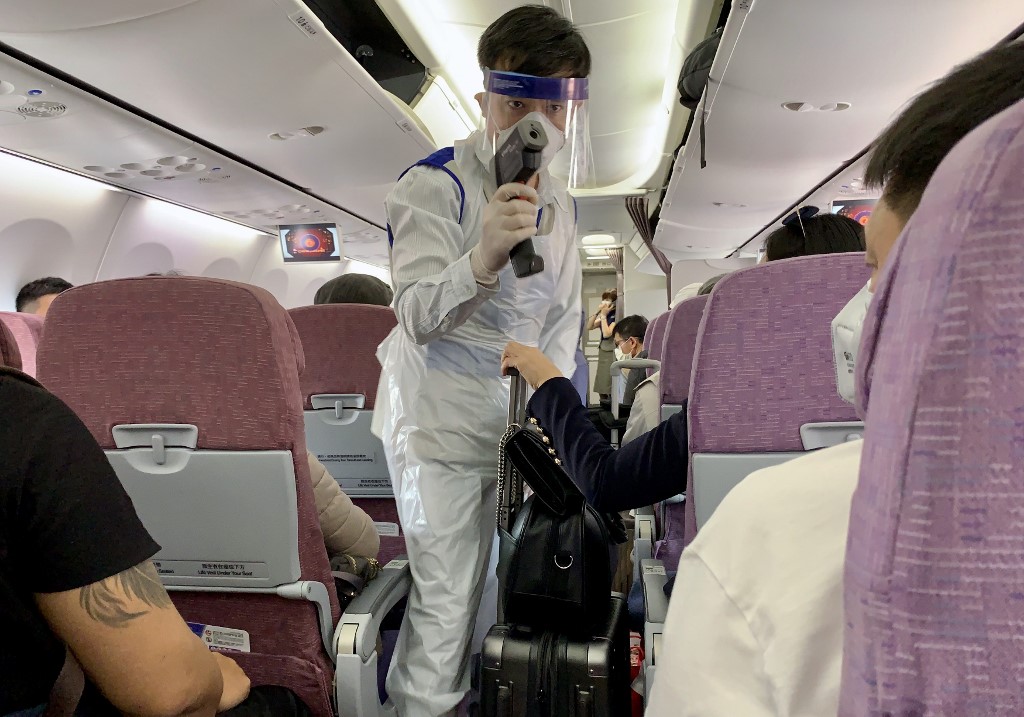  A member of the Myanmar health department wears protective gear as he approaches an airline passenger to check their temperature after the flight landed at Yangon International Airport in Yangon on February 19, 2020. (Sam Yeh / AFP)