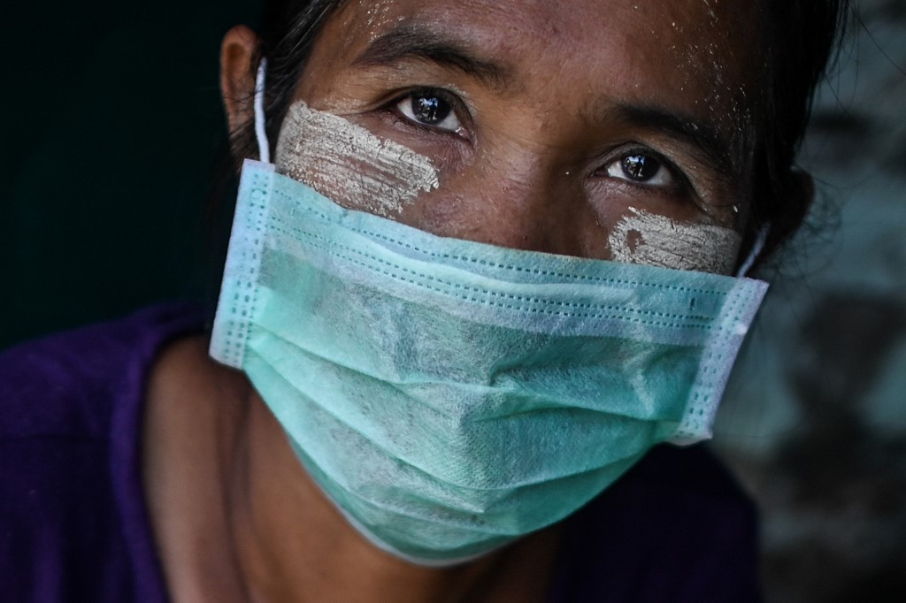 A vendor having thanaka, a traditional facial cosmetic wears a face mask as a preventive measure against the COVID-19 novel coronavirus at a market in Yangon on March 24, 2020. (Ye Aung Thu / AFP)