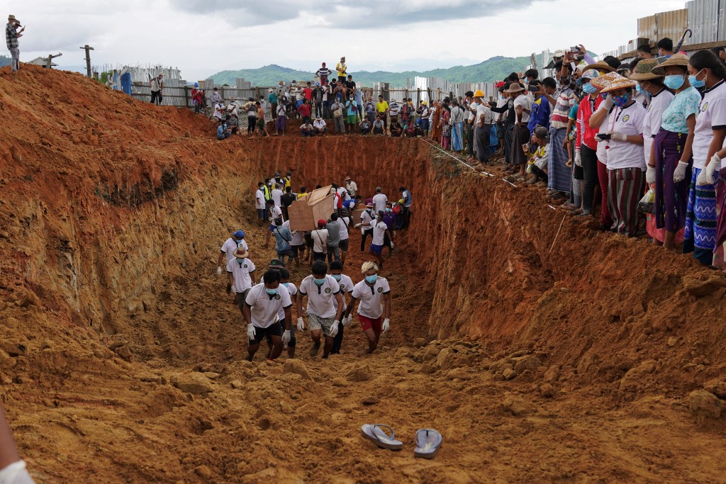 Volunteers bury bodies of miners in a mass grave while relatives look on during a funeral ceremony near Hpakant in Kachin state on July 3, 2020. (Zaw Moe Htet / AFP)