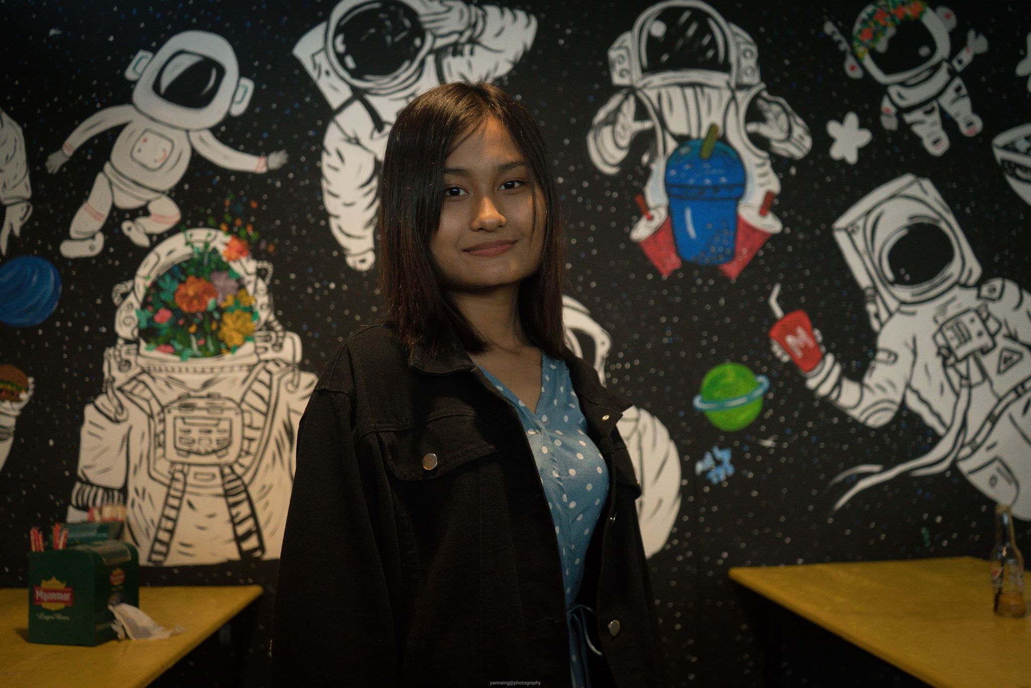 Thet Thet Soe, 19, poses in front of one of her wall paintings at Mario Juice and Snack Bar in Loikaw. (Yan Naing Aung)