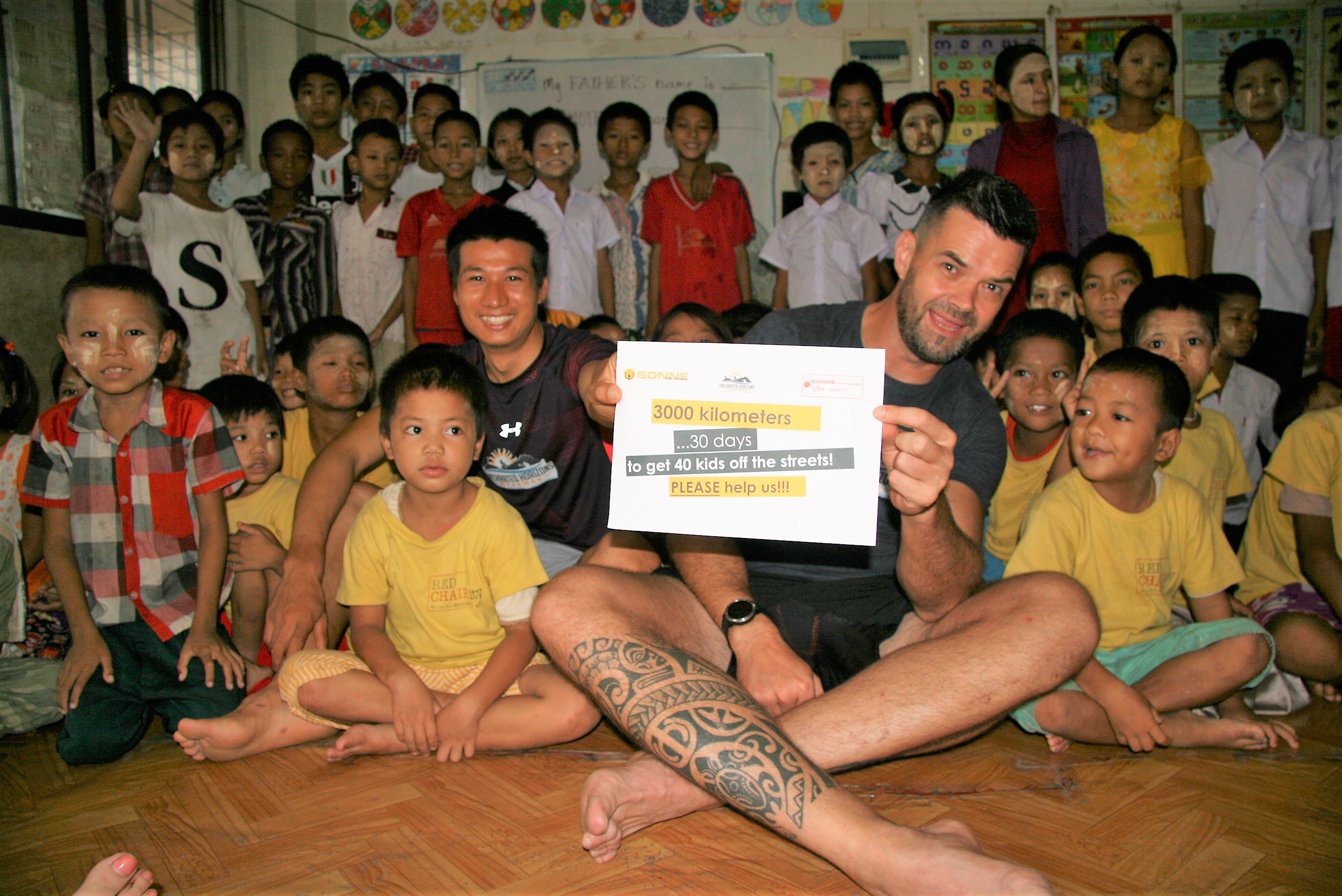 Kyaw Min Naing and Jochen Meissner with some of the children supported by SONNE Social Organisation. (Supplied)