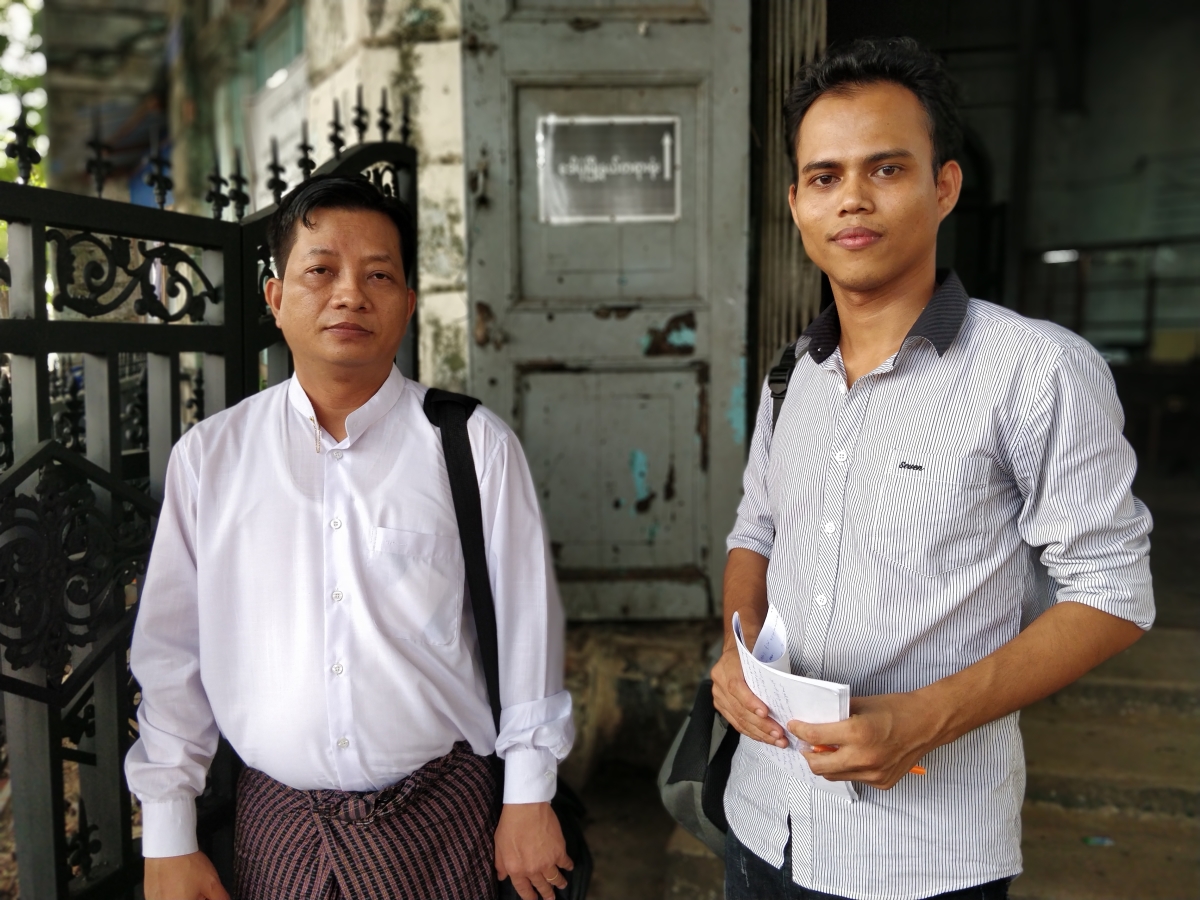 Journalist Moe Myint, right, stands in front of the Kyauktada township court with defence lawyer Than Zaw Aung on Wednesday. (Myanmar Now)