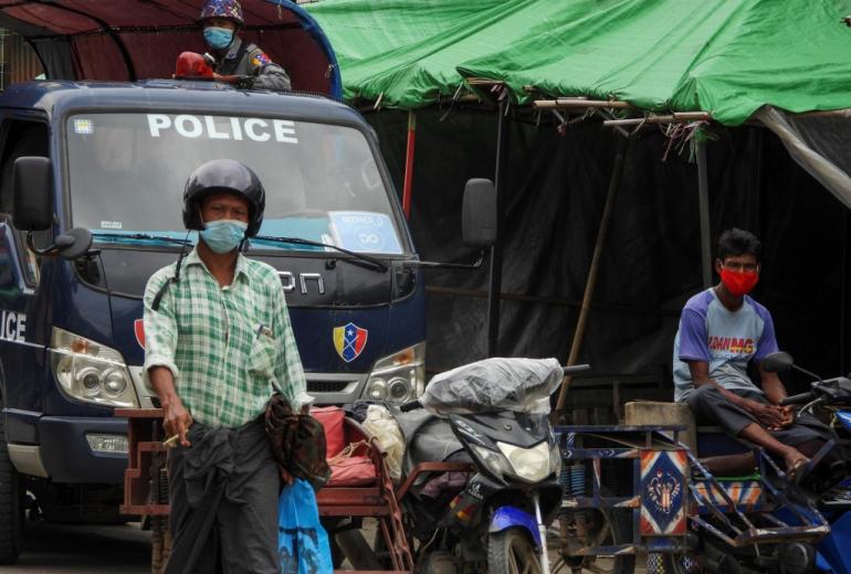 A police watches over from a vehicle while people wear face masks on a street on August 23, 2020 during a lockdown amid fears of the Covid-19 coronavirus in Sittwe. (AFP)