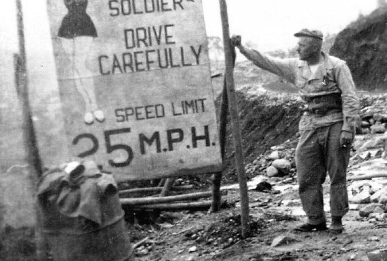 A soldier stands next to a sign on the Stilwell Road during World War Two. (CBI-Theater) 