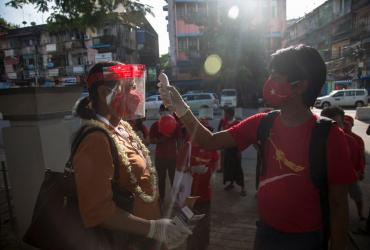 A National League for Democracy supporter checks the temperature for a fellow activist as they launch the campaign for the upcoming November 8 general election in Yangon on September 8, 2020. (Sai Aung Main / AFP)