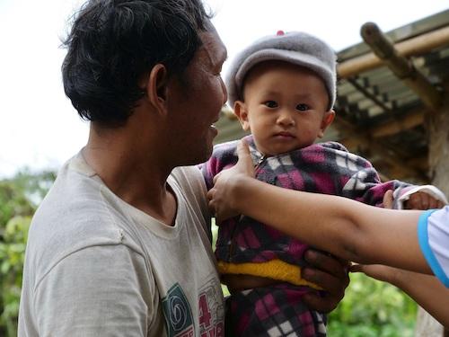 U Po Zo holds his grandson outside his home on Indawgyi lake. (Face of Indawgyi)